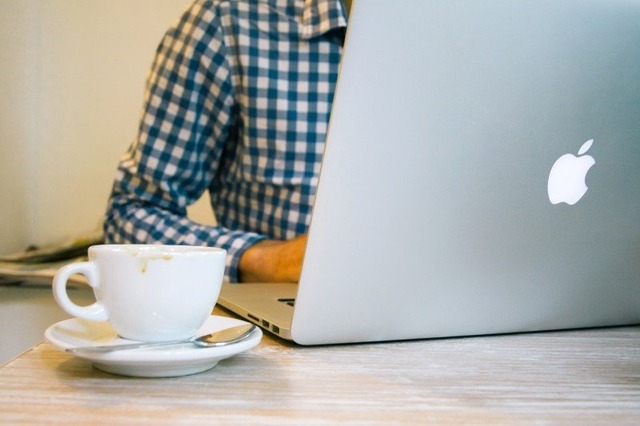 man-working-on-laptop-with-coffee-cup-in-foreground
